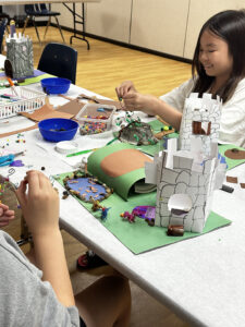 Kids make a castle out of paper, beads, and other supplies.