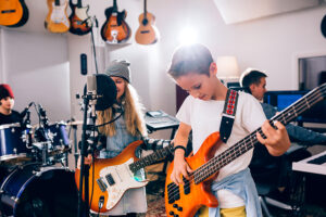 A young boy playing a guitar and a young girl singing into a microphone.