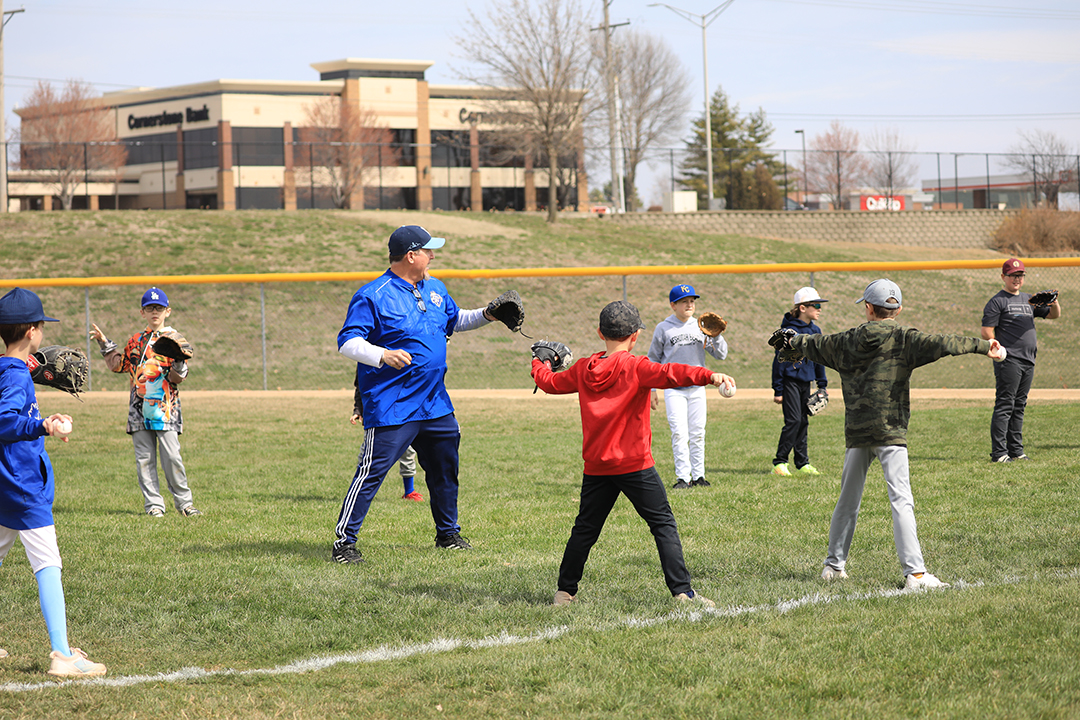 Baseball camp coach and campers practice throwing a baseball.