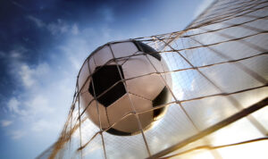 Photo of soccer ball going through a net.
