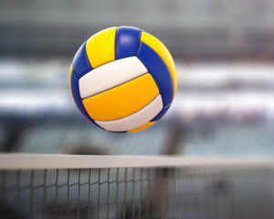 Photo of volleyball going over a net.