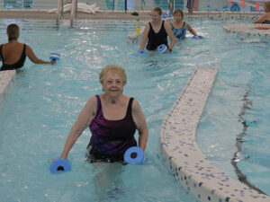 Senior female using floatation devices to walk in a lazy river.