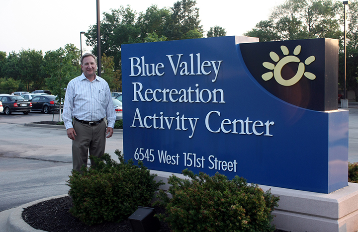 A man standing next to the entrance sign of the Activity Center.