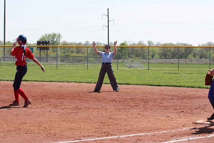 A female umpire signals a timeout during a softball game.