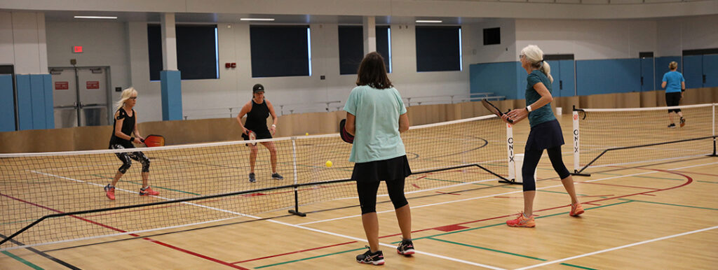 A ground of four females playing pickleball.