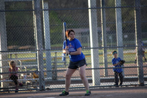 A female standing at home plate awaiting a pitch.