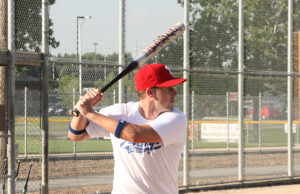 Adult male holding a softball bat waiting on a pitch.