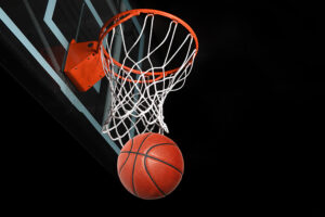 A basketball going through the net of a basketball goal.
