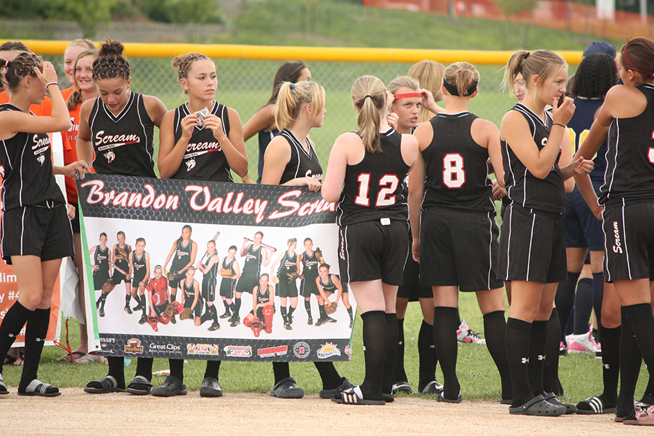 Youth softball teams holds a team banner during a youth softball tournament introduction at Blue Valley Rec Sports Complex