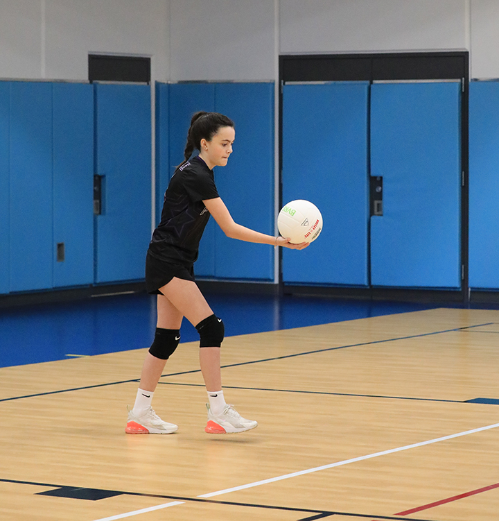 A young girl serves a volleyball during Spring Youth Volleyball League match.