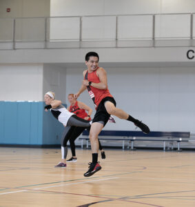 A fitness class participant performs a kick jump.