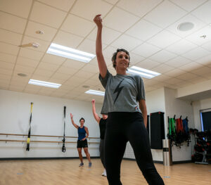 Participants raise a hand during a dance fitness class.