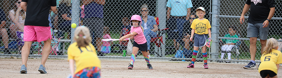 Young softball player swings a bat at the ball.