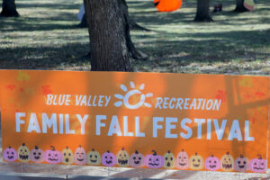 An orange banner advertising Family Fall Festival positioned between two trees.