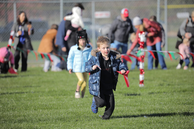 A young boy holding a candy cane runs to find more candy canes.