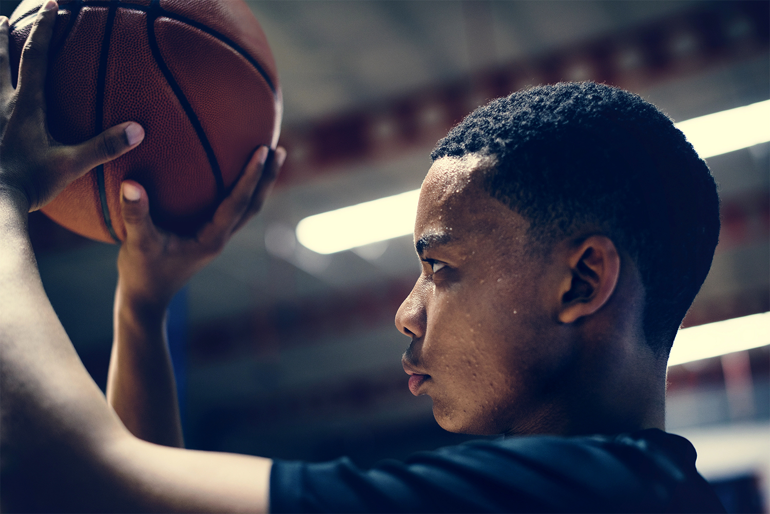 An African American boy practices shooting a basketball.