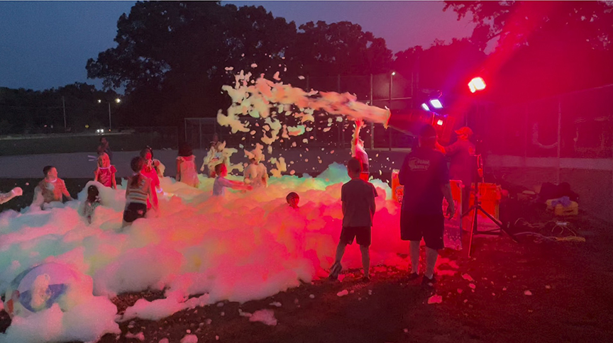 kids play in foam lit by colorful lights.