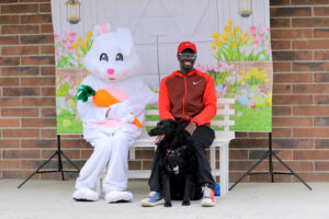 A man and his dog sitting for a photo with the Easter bunny.