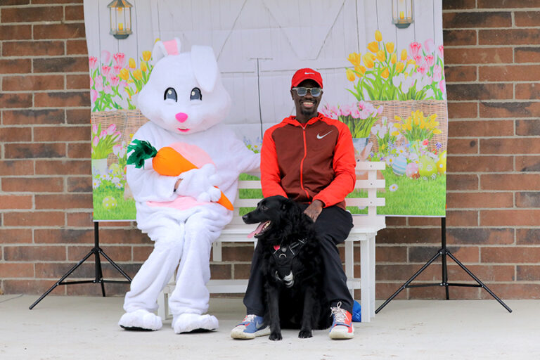 A man and his dog sitting for a photo with the Easter bunny.