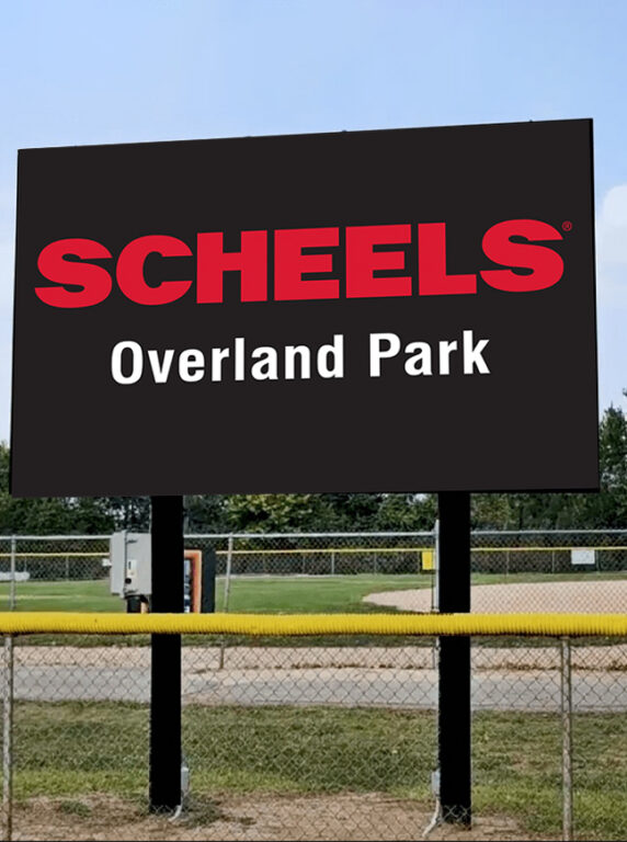 Sign displaying "SCHEELS Overland Park" at a baseball and softball complex.
