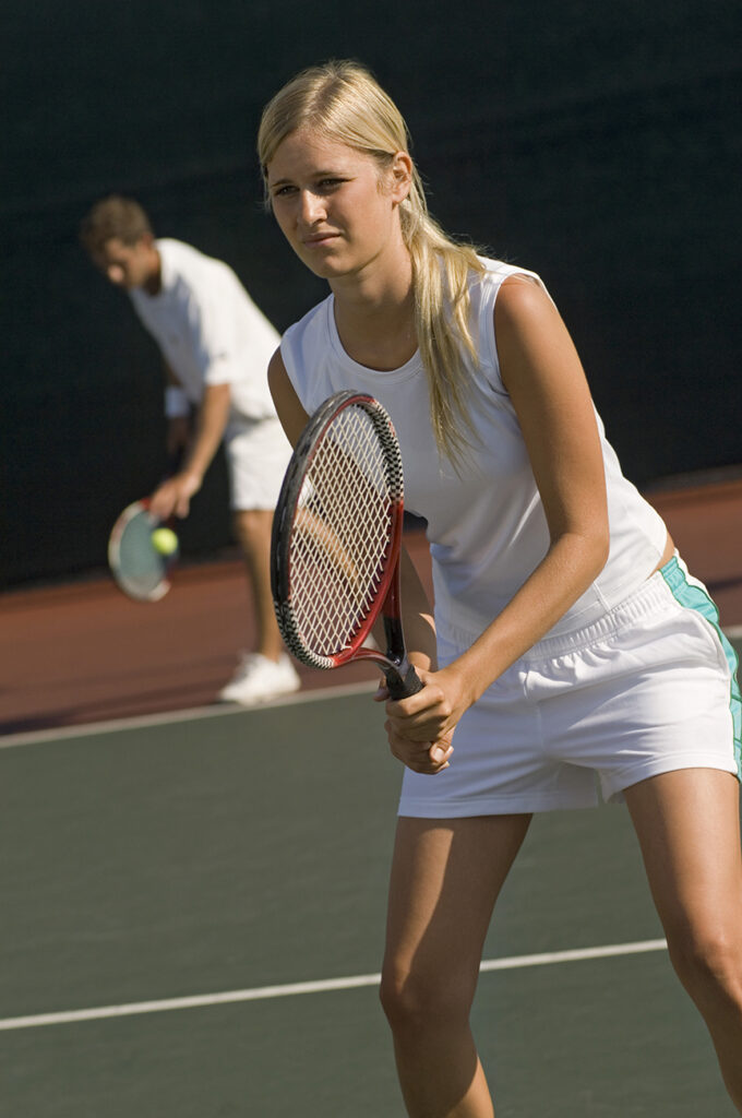 Adult tennis player in a ready position holding a racquet.