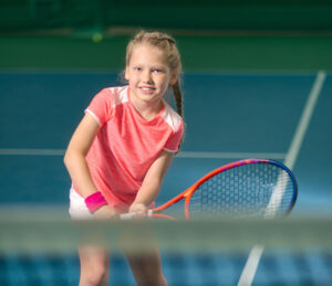 Young tennis player holding a racquet in a ready position.