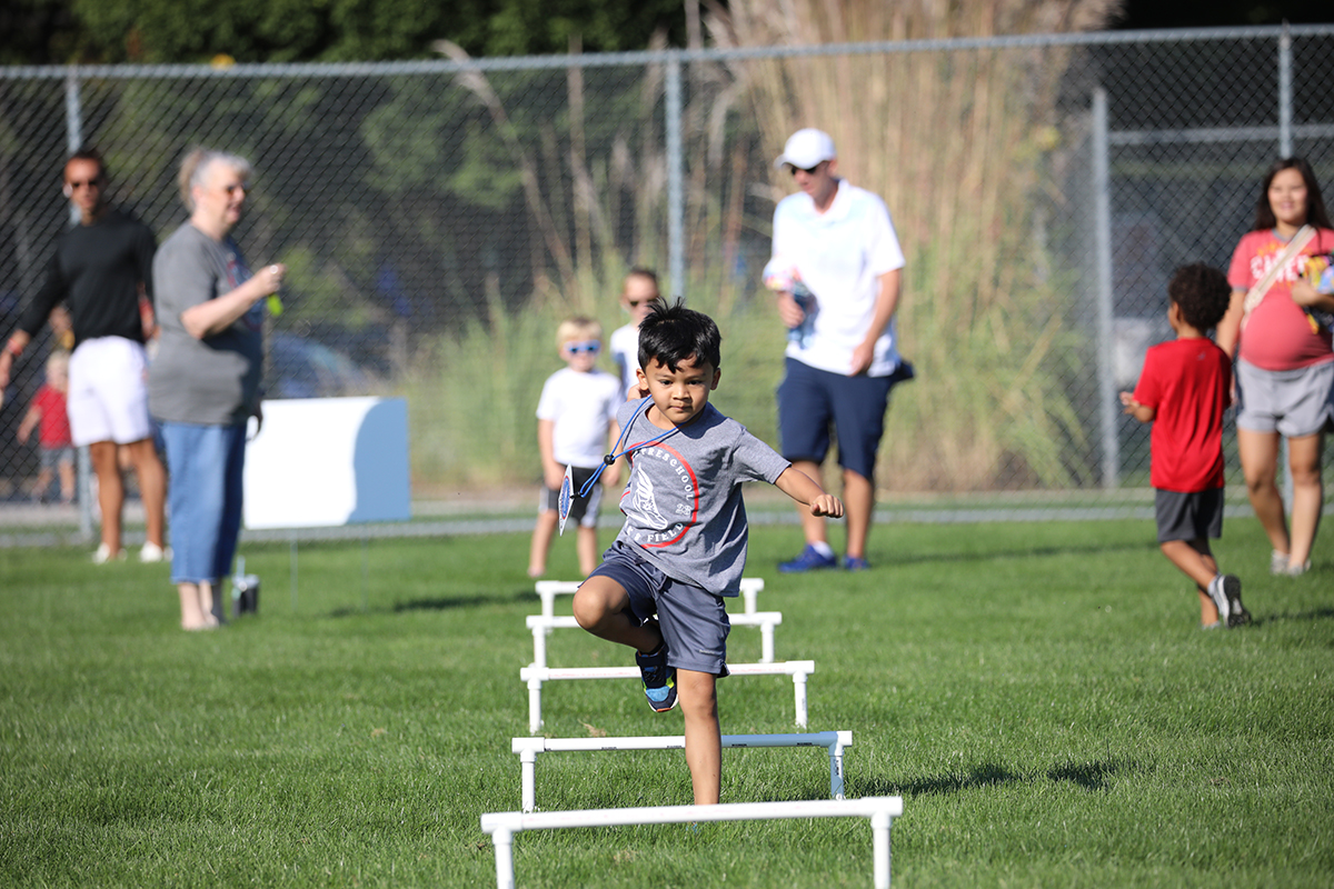 A young athlete jumps over small hurdles.